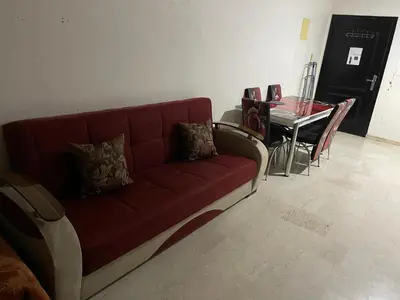 a living room with a red couch and a table at Appartement 26 au 4ème étage avec balcon ( POUR FAMILLE ) in Marrakech