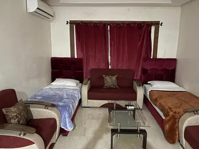 a room with two beds and a couch and a table at Appartement 26 au 4ème étage avec balcon ( POUR FAMILLE ) in Marrakech
