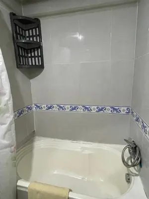 a white bath tub in a bathroom with blue and white tiles at Appartement 30 au 5 ème étage avec balcon ( POUR FAMILLE ) in Marrakech
