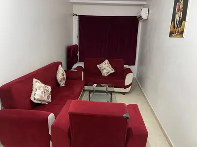 a living room with a red couch and chairs at Appartement 30 au 5 ème étage avec balcon ( POUR FAMILLE ) in Marrakech