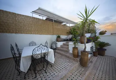 a patio with a table and chairs and potted plants at Riad Maison Belbaraka in Marrakech