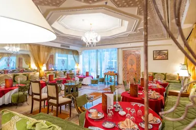 a restaurant with red tables and chairs and a chandelier at Kennedy Hospitality Resort in Marrakech