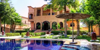 a house with a swimming pool and an umbrella at Palais Dar Ouladna in Marrakech