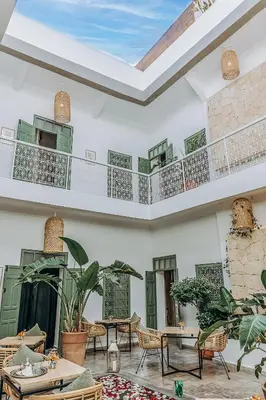 a living room with tables and chairs and a ceiling at Riad Villa Wengé & Spa in Marrakech
