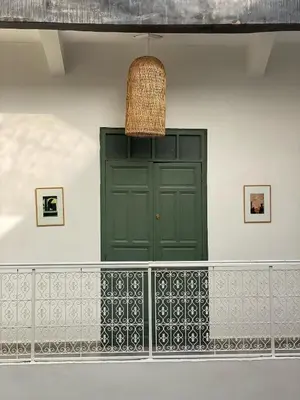 a green door in a white wall with a basket at Riad Villa Wengé & Spa in Marrakech