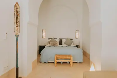a white bedroom with a bed and a table at Riad Djebel in Marrakech