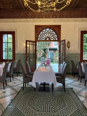 a dining room with a table and chairs and a chandelier at Pavillon du Golf - Palmeraie suites in Marrakech