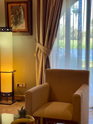 a living room with a chair and a window at Pavillon du Golf - Palmeraie suites in Marrakech