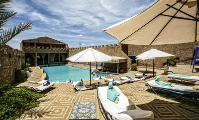 a pool with chairs and umbrellas next to a building at Hotel Kasbah Le Mirage & Spa in Marrakech