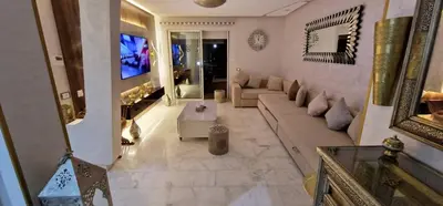 a large living room with a couch and a tv at Magnifique appartement à Riad Garden in Marrakech