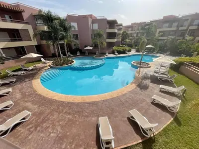 a large swimming pool with lounge chairs in a courtyard at Magnifique appartement à Riad Garden in Marrakech