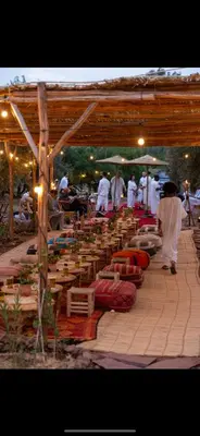 a group of people standing under a wooden structure at La Ferme des Tipis Marrakech in Marrakech