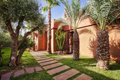 a house with palm trees and a walkway at Villa Ecolodge DAR LOUMA in Marrakech