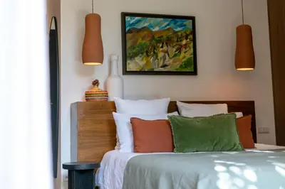a bedroom with a bed with colorful pillows and a painting at Villa Ecolodge DAR LOUMA in Marrakech
