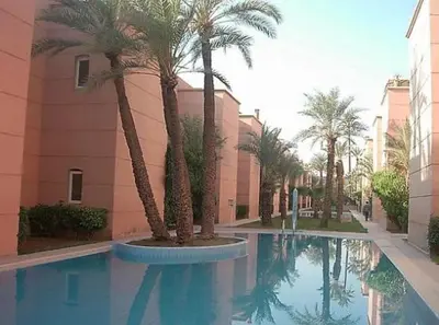 a swimming pool with palm trees in front of a building at Riad Jasmine in Marrakech