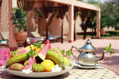 a plate of fruit on a table with a teapot at La Maison Des Oliviers in Marrakech