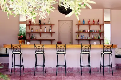 a bar with four stools in front of a counter at La Maison Des Oliviers in Marrakech