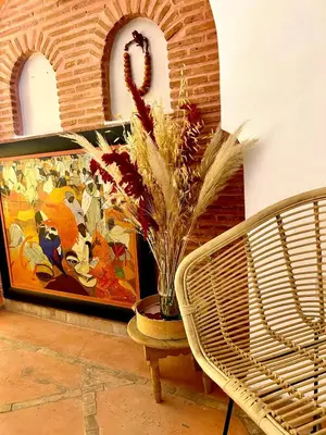 a vase of flowers on a table next to a painting at Riad Lauriers Blancs in Marrakech