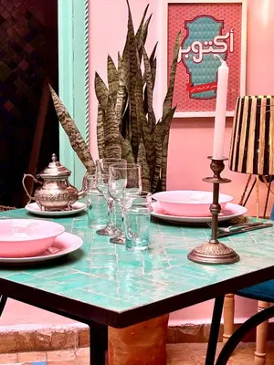 a table with a candle and plates and glasses on it at Riad Lauriers Blancs in Marrakech