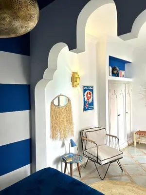 a bedroom with blue and white walls and a chair at Riad Lauriers Blancs in Marrakech