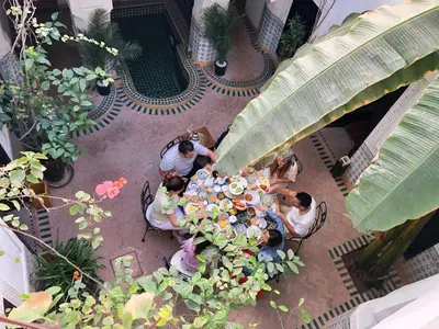 a group of people sitting at a table in a garden at Riad Al Mamoune in Marrakech