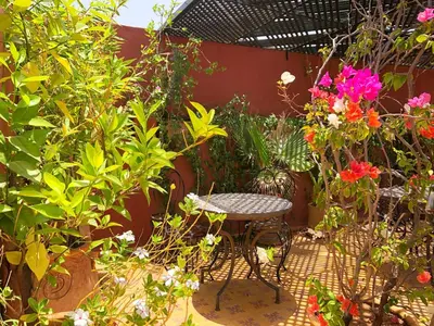 a table and chairs in a garden with flowers at Riad Al Mamoune in Marrakech
