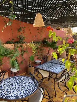 a patio with two tables and chairs and plants at Riad Al Mamoune in Marrakech