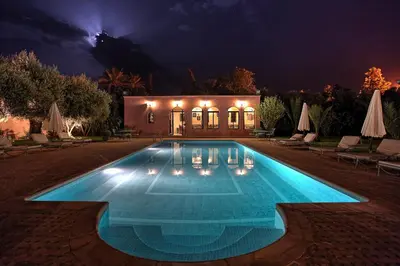 a swimming pool in front of a house at night at Villa Dar Mya Palmiers in Marrakech