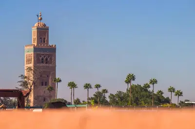 a clock tower with palm trees in the background at Riad Zinoun & Spa 11 Rooms in Marrakech