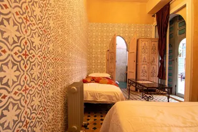 a bedroom with two beds and a patterned wall at Riad Zinoun & Spa 11 Rooms in Marrakech