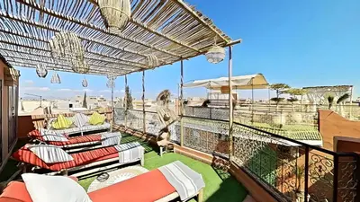 a balcony with chairs and tables on a roof at Riad El Grably in Marrakech