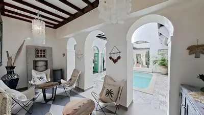 a living room with a table and chairs and a pool at Riad El Grably in Marrakech