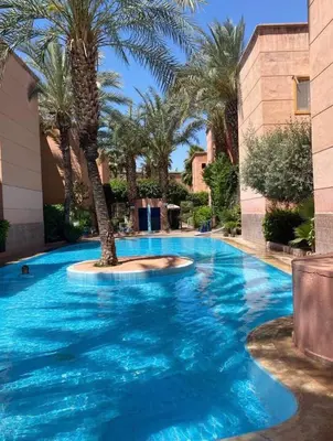 a large swimming pool with a palm tree in it at Riad jmiaa in Marrakech