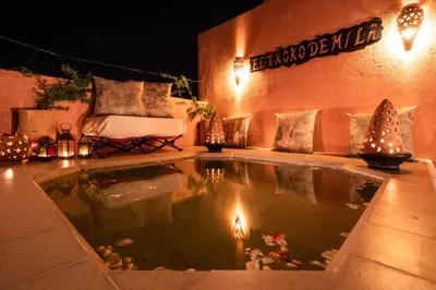 a swimming pool in a yard at night with lights at Riad Azcona in Marrakech