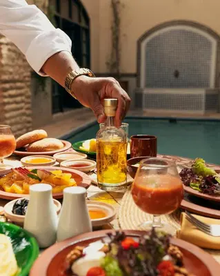 a person pouring a bottle of oil on a table of food at Marrakech Riads, Angsana Heritage Collection in Marrakech