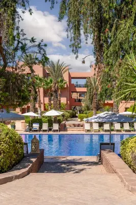 a resort swimming pool with umbrellas and chairs at Kenzi Menara Palace & Resort in Marrakech