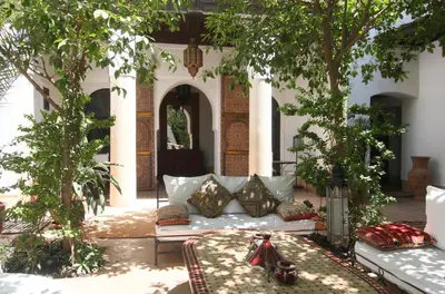 a couch in the middle of a courtyard with trees at Riad Karmela in Marrakech