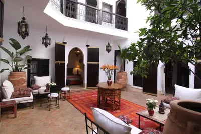 a large living room with tables and chairs and plants at Riad Karmela in Marrakech
