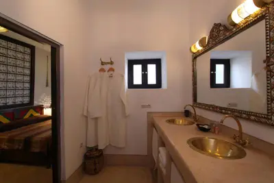 a bathroom with two sinks and a mirror and a bed at Riad Karmela in Marrakech