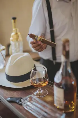 a man holding a cigar next to a bottle of wine at Les Deux Tours in Marrakech