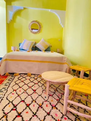a bedroom with a bed with a table and two benches at RIAD GALIYA in Marrakech