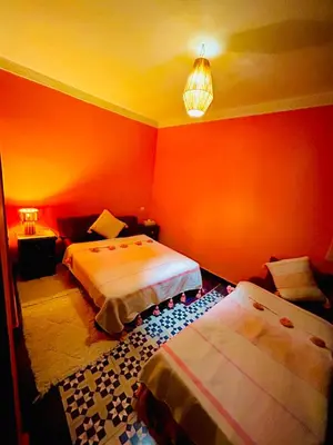 two beds in a room with orange walls at RIAD GALIYA in Marrakech