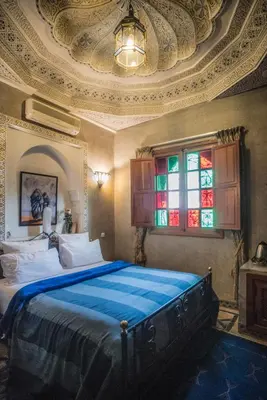a bedroom with a large bed and a stained glass window at Riad Mazal in Marrakech