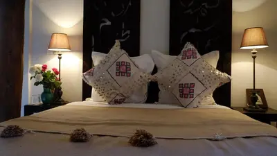 a bedroom with a bed with white pillows and two lamps at Riad Nafis in Marrakech