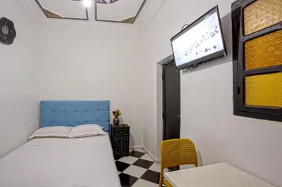 a room with a bed and a tv on the wall at Hotel Agnaoue in Marrakech
