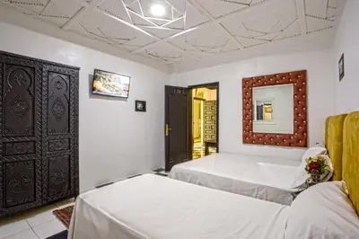 a bedroom with two beds and a mirror at Hotel Agnaoue in Marrakech