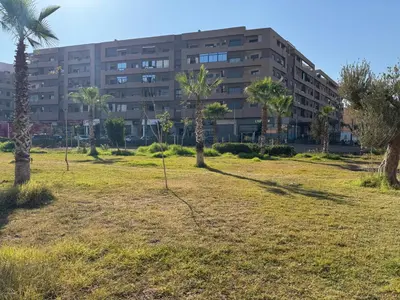 a building with palm trees in a field at Appart Kech Menera in Marrakech