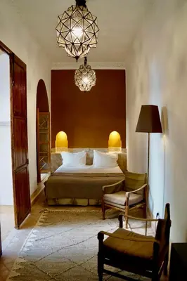 a bedroom with a bed and a chair and a chandelier at Riad Tzarra in Marrakech