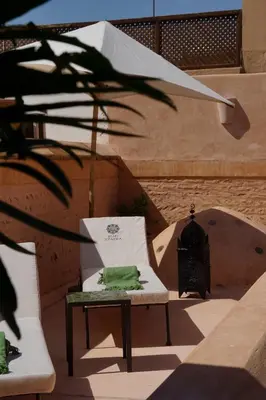 a white chair with a green pillow on it at Riad Tzarra in Marrakech