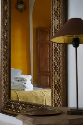 a mirror on a table next to a bed with towels at Riad Tzarra in Marrakech